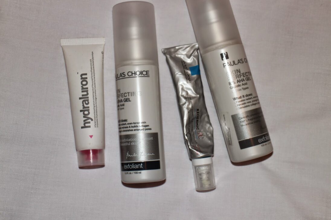 Paula’s Choice BHA and AHA gels, Hydraluron serum, and a tube of La Roche-Posay Redermic on a white background.