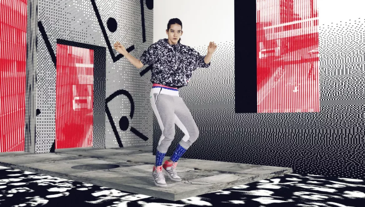 Model dancing in printed windbreaker and grey cropped joggers by Adidas StellaSport