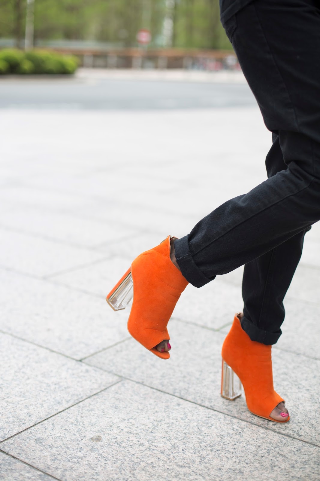 Close-up detail shot of vibrant bright orange statement heels on pavement